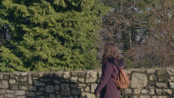 Young woman walks next to a large green forest on her trip through Europe