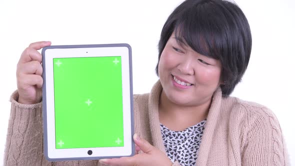 Face of Happy Overweight Asian Woman Showing Digital Tablet Ready for Winter