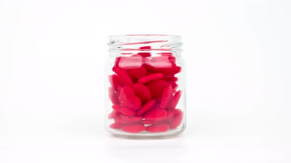 Stop motion animation small red heart into a clear glass jar isolated on white background.
