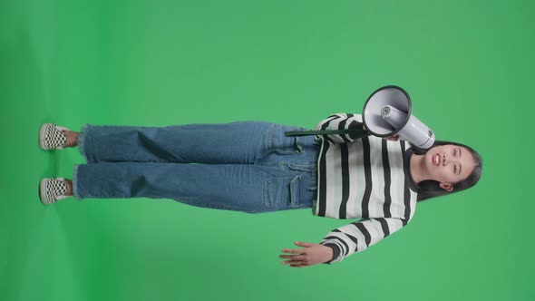 Full Body Of An Asian Woman Speaking On Megaphone In The Green Screen Studio