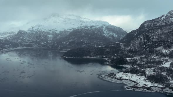 Flying above a frosen lake between Mountains in fogy day in Norway in december 2018