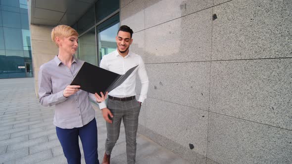 Diverse Multiracial Colleague Discuss Business Hold Folder with Document Walking Together at Modern