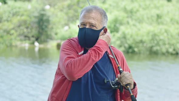 Close-up of Senior Man with Intense Look Wearing a Protective Face Mask in Front of a Lake