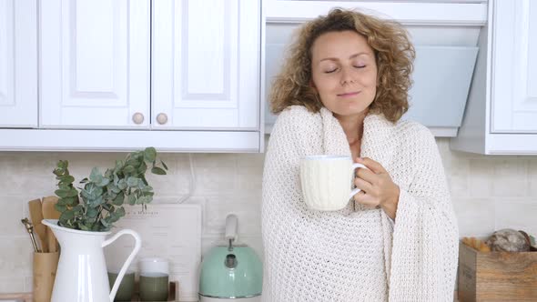 Homey Woman With Dreamy Look Holding Cup Of Tea At Home Kitchen