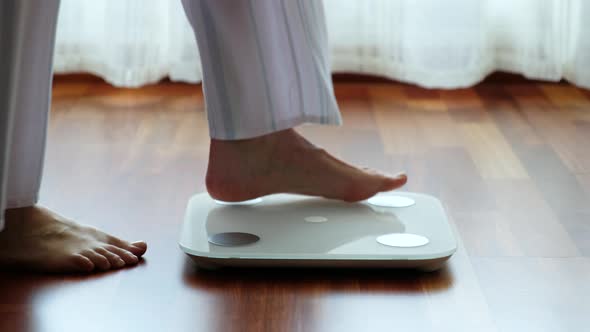 Crop woman standing on digital weight scales