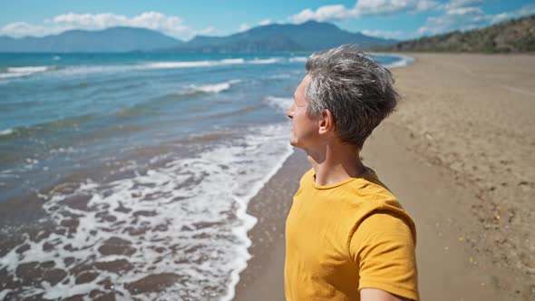 Close Up Portrait of Middle Aged Greyhead Man at Sea Coast Enjoys Sunny Day and Fresh Air on