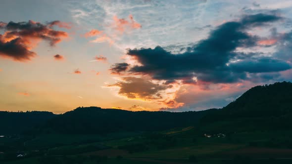 aerial hyperlapse at sunset over swiss countryside. dramatic moving clouds in sky with orange color