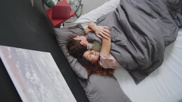 Woman Cuddling Husband while Sleeping on Bed