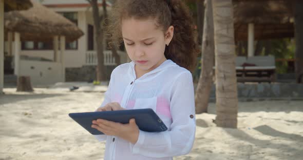 Curious Cute Girl 78 Years Old Is Having Fun with a Digital Tablet Device Watching a Cartoon While