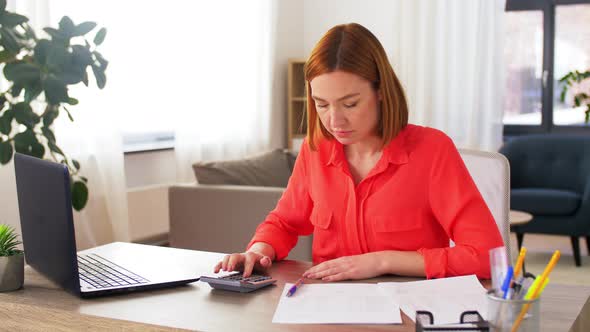 Woman with Calculator and Papers Working at Home