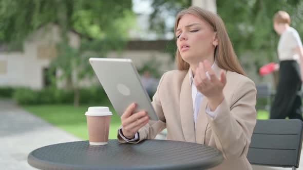 Young Businesswoman Reacting to Loss on Tablet in Outdoor Cafe