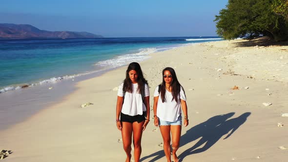 Beautiful ladies tanning on paradise shore beach break by turquoise lagoon and white sand background