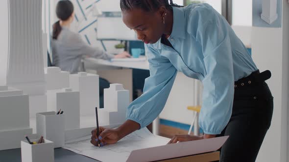 Engineer Working on Blueprints Plans on Desk to Design Building Model and Maquette