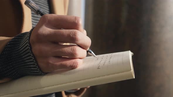 A Man's Hand Makes Notes in a Paper Notebook with a Pen Inspiration or Writes Down an Action Plan