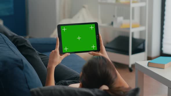 Woman Sitting on Sofa in Living Room Watching Movies on Tablet Computer