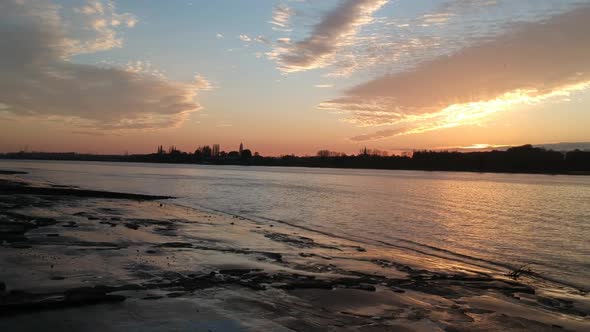 Silhouette of city buildings on river Schelde coastline, aerial side fly view