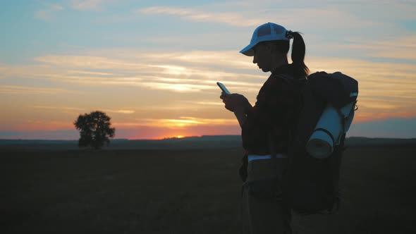 Silhouette of Young Tourist Woman Use Phone with Dramatic Sunset Sky Background. Always Connected