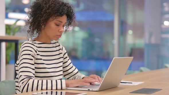 African Woman Celebrating Success on Laptop in Office