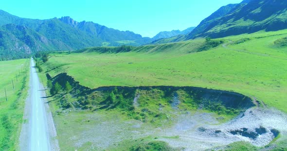 Aerial Rural Mountain Road and Meadow at Sunny Summer Morning. Asphalt Highway and River.