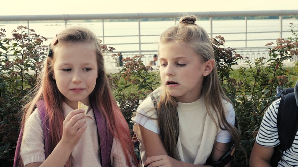 Girl eating corn chips sitting next to her friends.