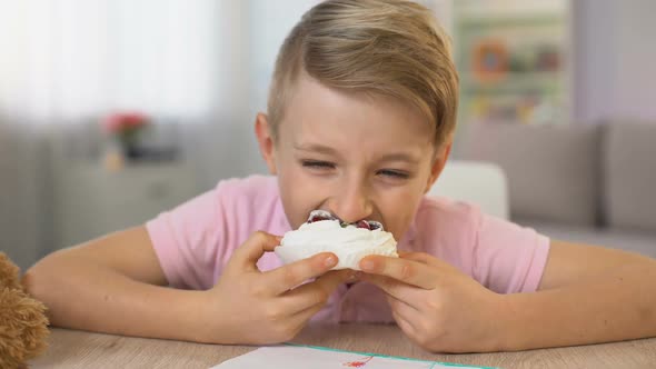 Cute Boy Eating Cream Dessert Sitting at Table, Sugar Overeating, Diabetes Risk