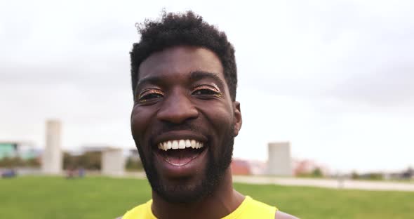 Young african man with make up smiling on camera at city park