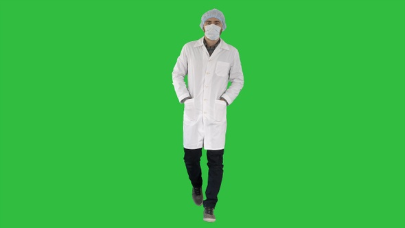 Walking young male doctor wearing surgical mask on a Green