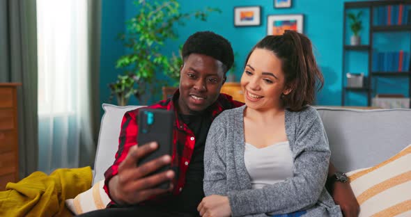 Man and Woman Making Video Call Taking Selfie Sitting on a Sofa Together at Home