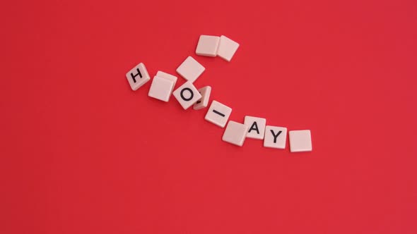 Letter tiles moving to spell out happy holidays on red background