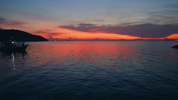 A Fisherman's Boat Sailing Alone in the Sea with a Colorful Sunset