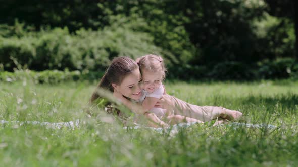 Family Time. Mother And Daughter Resting On Blanket At Park