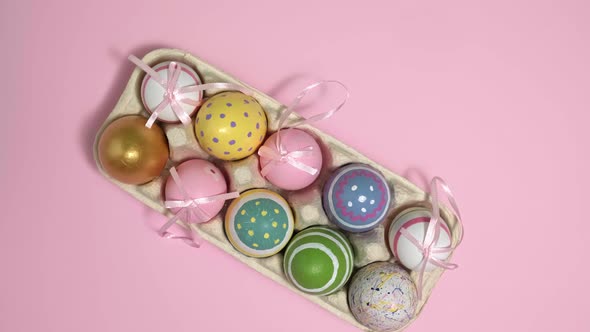 Rotating Colorful Easter Eggs In A Cardboard Box on Pink Background