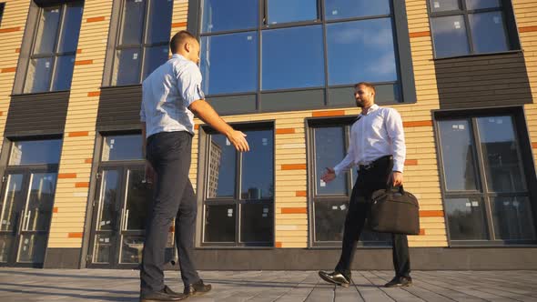 Young Male Coworkers Meeting Near Office Building and Greeting Each Other