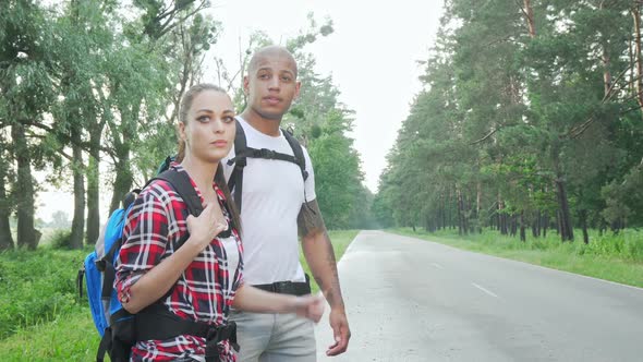 Beautiful Multiracial Couple Hitchhiking on Countryside Road