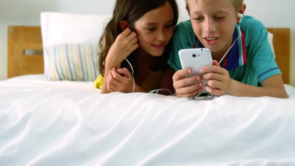 Siblings using mobile phone in bedroom