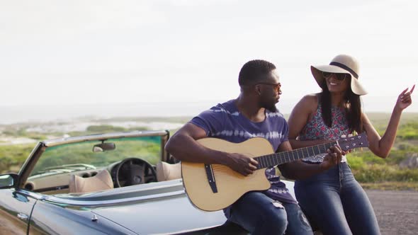 African american man playing guitar for his girlfriend while standing on the road