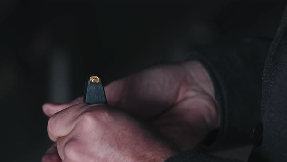 A Man Sticks Bullets Into a Gun Magazine