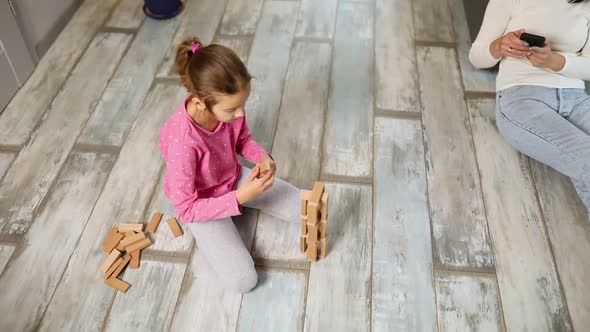 Indifferent Mother Use Mobile Phone Daughter Play Wooden Construction