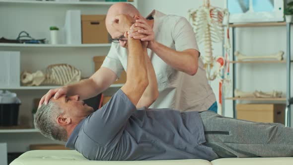 The Doctor Conducts a Physiotherapy Session with an Older Man With a BrainStroke