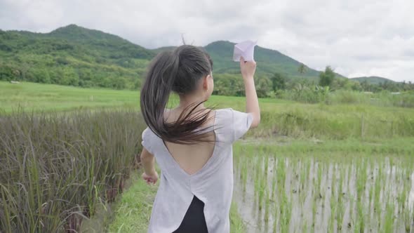 Girl Running With A Paper Airplane In Rice Field