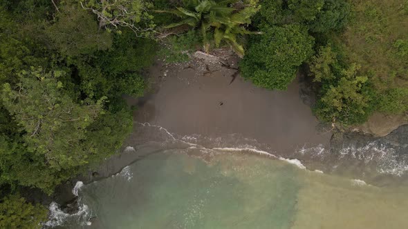 aerial top down view of the waves landing on a sandy beach on the Costa Rican coast