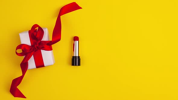 Stop motion animation of white gift present with red bow and red lipstick on the left on yellow