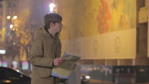 Young Man Lost in Big City, Looking at Map, Asking Passer-By to Show Right Way