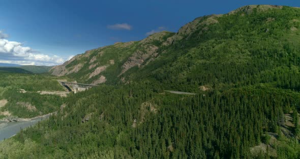 Mountain Road Bridge Aerial View with A Motorcade of Three White R vs Approaching It