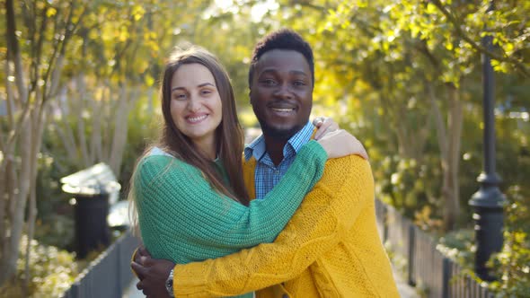 Affectionate Multi-ethnic Couple Embracing and Smiling Outdoors