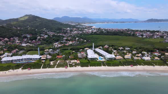 Aerial drone view of tourist beach with several summer houses facing the sea with lots of vegetation