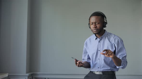 AfricanAmerican Man with Headphones Turns on the Music and Begins to Dance Energetically