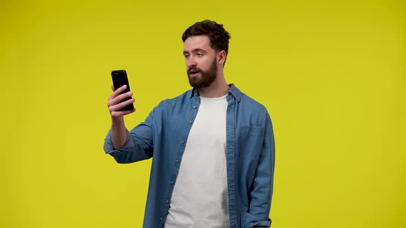 Portrait of a Man Making a Video Call on His Phone Waving His Hand Greeting the Interlocutor