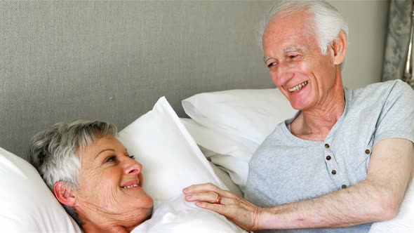 Senior couple interacting with each other on bed in bedroom