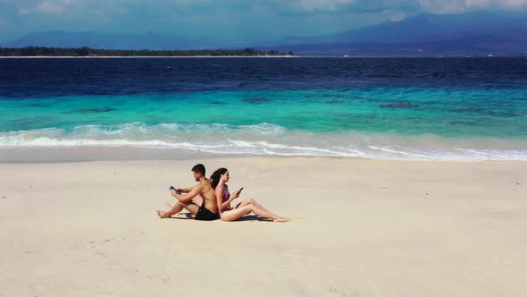 Teenage lovers tanning on beautiful tourist beach journey by turquoise sea with white sand backgroun